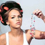 Гламурная брюнетка с красной лентой в волосах держит в руке бусики; анимированная аватарка 150×150px